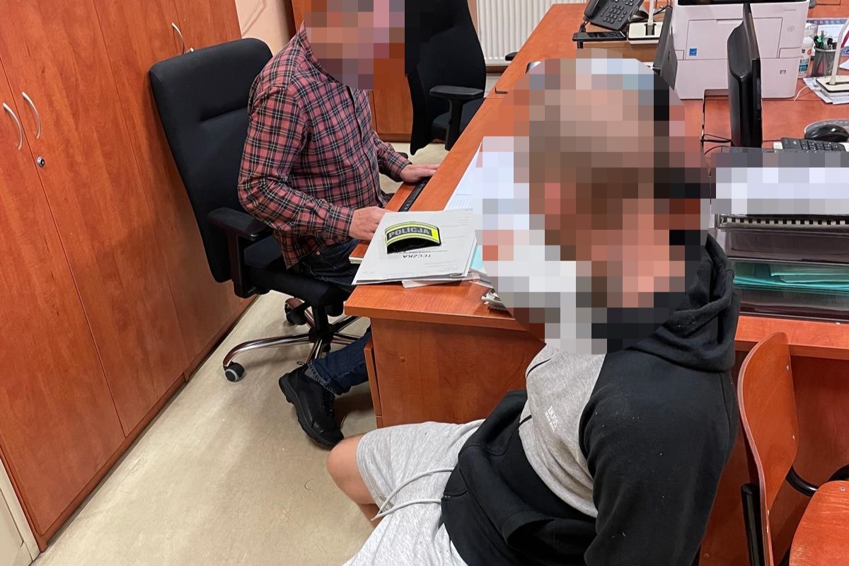na zdjęciu zatrzymany przy biurku, gdzie siedzi kryminalny 
