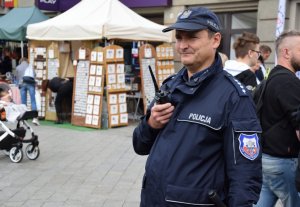 Na fotografii widać policjanta, który trzyma w dłoni radiotelefon.
