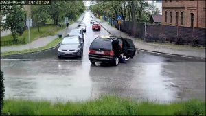 na zdjęciu widać jak z samochodu osobowego skręcającego w lewo w ulicę, wypada dziecko. Z lewej strony zdjęcia widać inne samochody