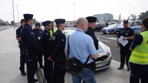 Na zdjęciu widać Komendanta Powiatowego Policji w Tarnowskich Górach młodszego inspektora Sławomira Bylickiego wraz z innym policjantami podczas odprawy służbowej odbywającej się przed terminalem lotniska.