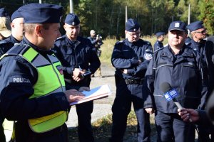 Grupa policjantów stoi w okręgu. Wśród nich znajduje się dowódca działań i Komendant KPP Tarnowskie Góry