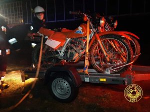 Na zdjęciu widać motocykle, które strażak zdejmuje z przyczepki