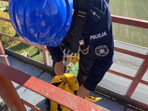 Policjanci podczas szkolenia z ratownikami CSRG. Policjant w kasku ochronnym z żółta torbą.