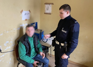 na zdjęciu policjant bada trzeźwość zatrzymanego mężczyzny, który siedzi na krześle