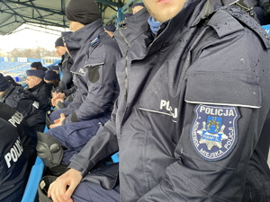 na zdjęciu naszywka na niebieskim mundurze z napisem Policja Komenda Miejska Policji w Piekarach Śląskich, w tle inni policjanci