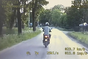 na zdjęciu wycinek z policyjnego wideo rejestratora, na którym widoczny jest uciekający mężczyzna na skuterze, który porusza się jezdnią
