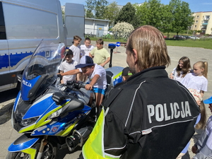 na zdjęciu policjant przy motocyklu, na którym siedzi dziecko