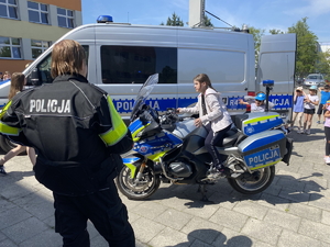 na zdjęciu policyjny motocykl a na nim dziecko, wszystko obserwuje policjant