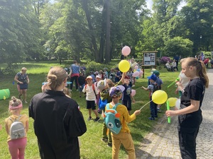 na zdjęciu uczennice klasy mundurowej trzymające w ręku balony i puszczające mydlane bańki, przed nimi biegające dzieci