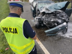 na zdjęciu policjant przed rozbitym pojazdem