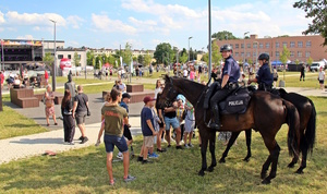 na zdjęciu policjanci koniach a przed nimi dzieci i miejsce imprezy