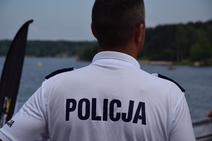 na zdjęciu policjant w białej koszulce z napisem policja, przed nim akwen wodny