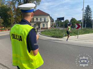 na zdjęciu policjant w odblaskowej kamizelce na trasie biegu