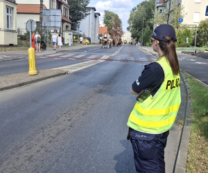 na zdjęciu policjantka na jezdni, w oddali koniec i inne osoby