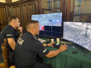 na zdjęciu policjanci siedzący przy monitorach z monitoringiem