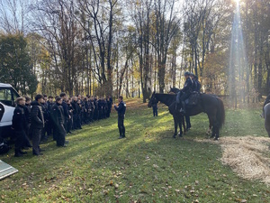 na zdjęciu policjanci na konia przed młodzieżą stojąca na trawie w dwuszeregu