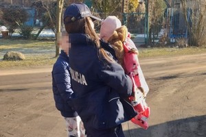 na zdjęciu policjantka z dzieckiem na rękach w trakcie ewakuacji