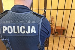 na zdjęciu policjant przed celą, a w niej kobieta