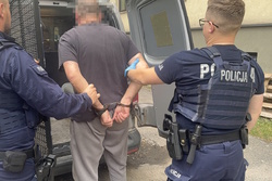 na zdjęciu policjanci przed radiowozem z zatrzymanym