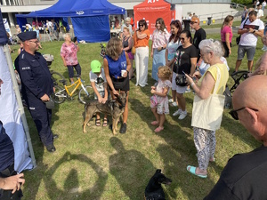 na zdjęciu policjant z psem, obok osoby