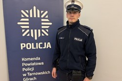 na zdjęciu policjant przy banerze z napisem policja komenda powiatowa policji w tarnowskich górach