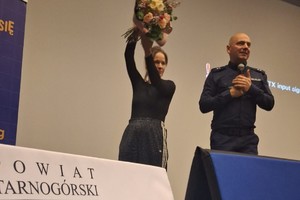 na zdjęciu kobieta z kwiatami i obok policjant