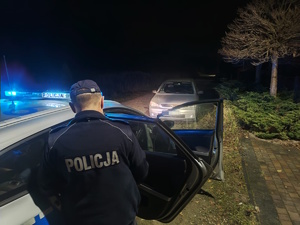 na zdjęciu policjant przy radiowozie, przed nim samochód osobowy