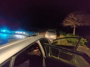 na zdjęciu fragment radiowozu i samochód osobowy przed nim