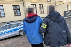 na zdjęciu policjant prowadzący zatrzymanego