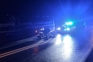 na drodze po zmroku osobowy bus, przy nim osoby i policjanci z radiowozem kierujący ruchem