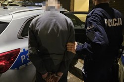 na zdjęciu policjant z zatrzymanym przy radiowozie