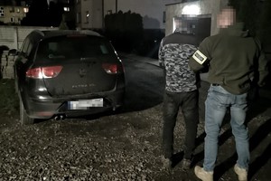 na zdjęciu policjant po cywilu z zatrzymanym obok samochodu