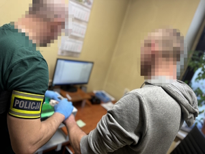 na zdjęciu policjant i zatrzymany w trakcie pobierania odcisków palców