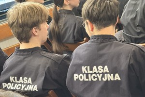 na zdjęciu uczniowie klasy policyjnej w mundurach w sali na krzesłach tyłem do obiektywu