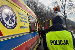 na zdjęciu policjant z urządzeniem na jezdni przy karetce