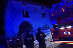 na zdjęciu policjanci przy wozie strażacki przed budynkiem