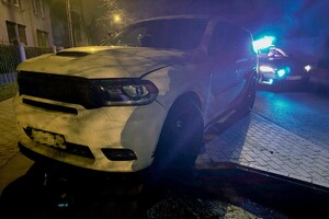 na zdjęciu biały samochód osobowy, a za nim policyjny radiowóz