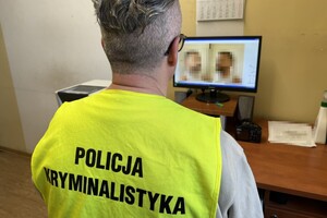 na zdjęciu policjant w kamizelce z napisem technik kryminalistyki przed ekranem monitora