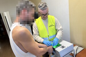 na zdjęciu policjant w kamizelce z napisem technik kryminalistyki, a obok niego zatrzymany mężczyzna