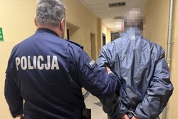 na zdjęciu policjant z zatrzymanym w korytarzu