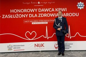 na zdjęciu policjant a za nim napis honorowy dawca krwi - zasłużony dla zdrowia narodu