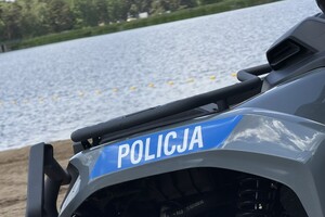 fragment quada z naklejką z napisem policja, w oddali akwen