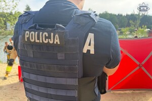 na zdjęciu policjant przed czerwonym parawanem na plaży