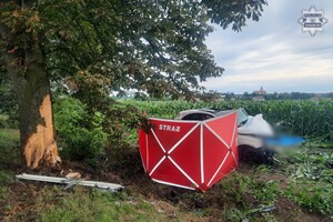 na zdjęciu czerwony parawan przy drzewie, za parawanem uszkodzony pojazd