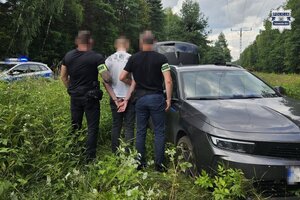 na zdjęciu policjanci z zatrzymanym przy pojeździe