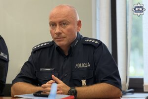 na zdjęciu policjant siedzący za stołem