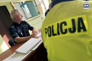 na zdjęciu policjant za biurkiem