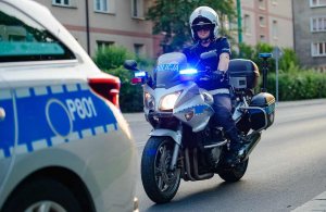 Na zdjęciu widoczny policjant na motorze oraz kawałek radiowozu