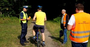 Policjant z drogówki rozmawia z rowerzystą, wokół stoi funkcjonariusz SOK oraz polskich linii kolejowych.