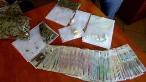 Amfetamina, marihuana oraz pieniądze rozłożone na biurku.